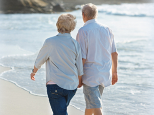 Older couple walking on the beach representing long term care coverage.